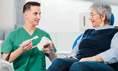 Mundhygiene-Beratung: Zahnmodell und Zahnbürste im Gespräch mit einer Patientin, Zahnarzt Dornbirn