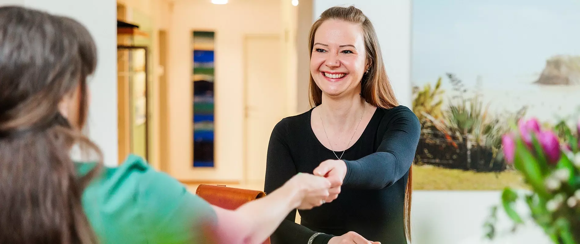 Herzlicher Empfang in der Zahnarztpraxis Kupec in Dornbirn: Mitarbeiterin begrüßt Patientin per Handschlag